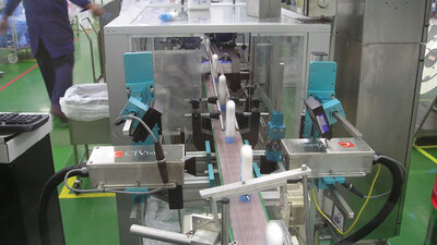 Shampoo bottles being inspected by cameras along conveyor